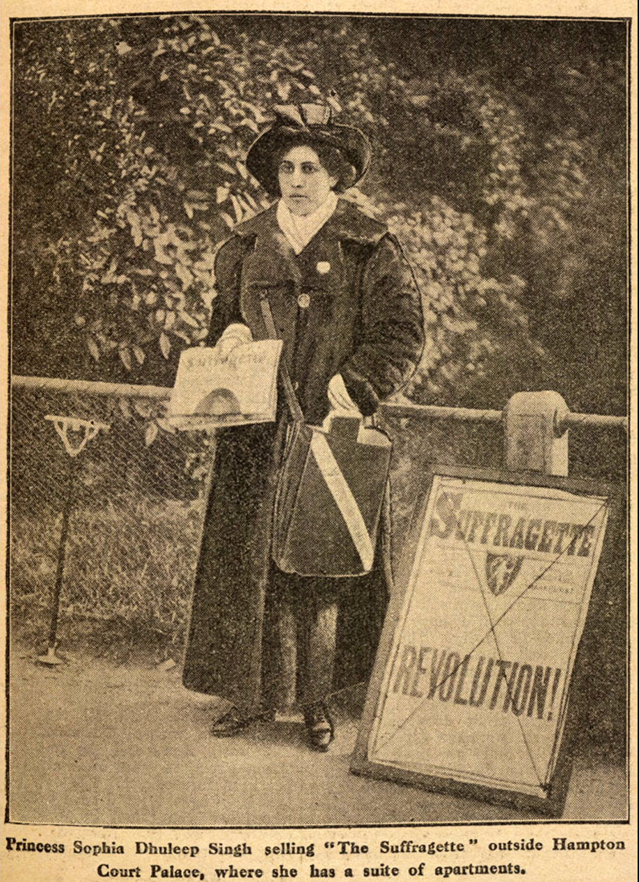 Newspaper clipping of a woman in Victorian era clothing holding a newspaper. She is standing next to a placard that reads Suffragette Revolution